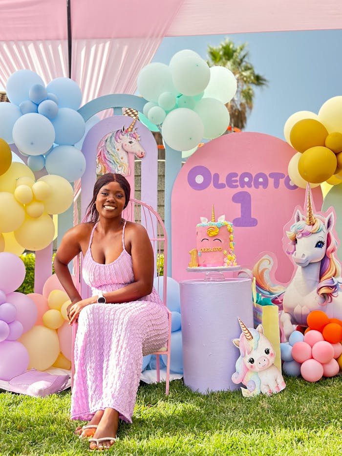 A woman sitting in front of a unicorn themed birthday party